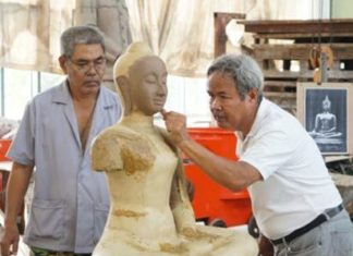 The sculptor, Master Kongket, is applying wax to the surface of the clay body in order to finish the detail decoration especially the face of the Buddha image.